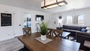 Una sala moderna con una mesa de comedor de madera, un sofá y un ventanal con vistas.
