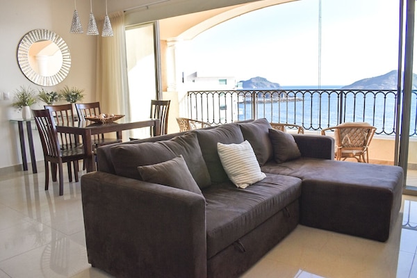Living and dining room with ocean view and fully opening glass doors.