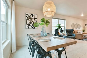 Un comedor moderno con una mesa de madera, sillas negras y una lámpara colgante.