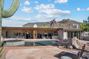 Ein modernes Haus mit Swimmingpool, Terrassenmöbeln und Bergblick.