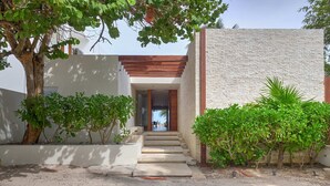 A modern building with a stone facade, a wooden staircase, and surrounding greenery. - Casa Kux  -  Yucatan Home Rentals (Chicxulub Puerto)