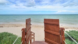 A wooden beach gate leading to a sandy beach with calm sea and a partly cloudy sky. - Casa Kux  -  Yucatan Home Rentals (Chicxulub Puerto)