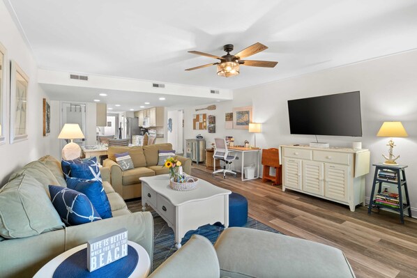 A modern living room with a sofa, coffee table, TV, and a ceiling fan.