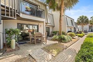 A modern building with a balcony, outdoor seating, and a well-maintained garden.