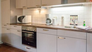 A kitchen with white cabinets, a microwave, a coffee maker, and a sink. - Senwai-Hüs, Whg. 1 Braderup - Senwai-Hüs (Sylt)
