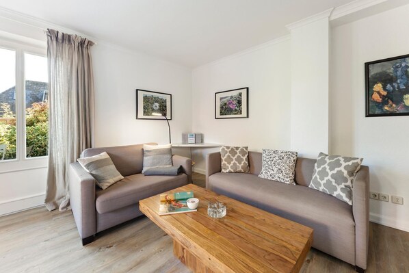 A living room with two sofas, a coffee table, and a window with curtains.