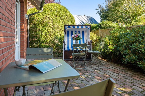 A patio with a table, chairs, and a small structure with a striped awning. - Senwai-Hüs, Apartment 1, Braderup - Senwai-Hüs (Sylt)