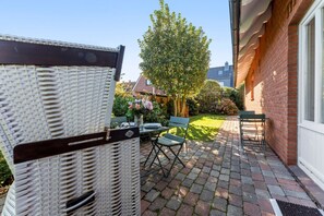 A patio with outdoor furniture, a brick wall, and a garden with a tree and flowers.