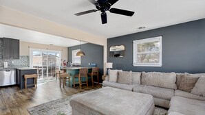 A modern living room with a large beige sectional sofa, a dining area with a bar, and a kitchen with dark cabinets. - 3 Bedroom Mimosa Pool Oasis, Sleeps 8, Outdoor Shower &Hot Tub.Dog & EV Friendly (Cape May)