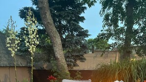 A square fire pit with a woven design, surrounded by outdoor furniture including a cushioned bench and a lounge chair. - 3 Bedroom Mimosa Pool Oasis, Sleeps 8, Outdoor Shower &Hot Tub.Dog & EV Friendly (Cape May)