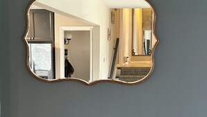 A room with a large, ornate mirror on the wall, a grey sofa, and a door leading to another room. - 3 Bedroom Mimosa Pool Oasis, Sleeps 8, Outdoor Shower &Hot Tub.Dog & EV Friendly (Cape May)