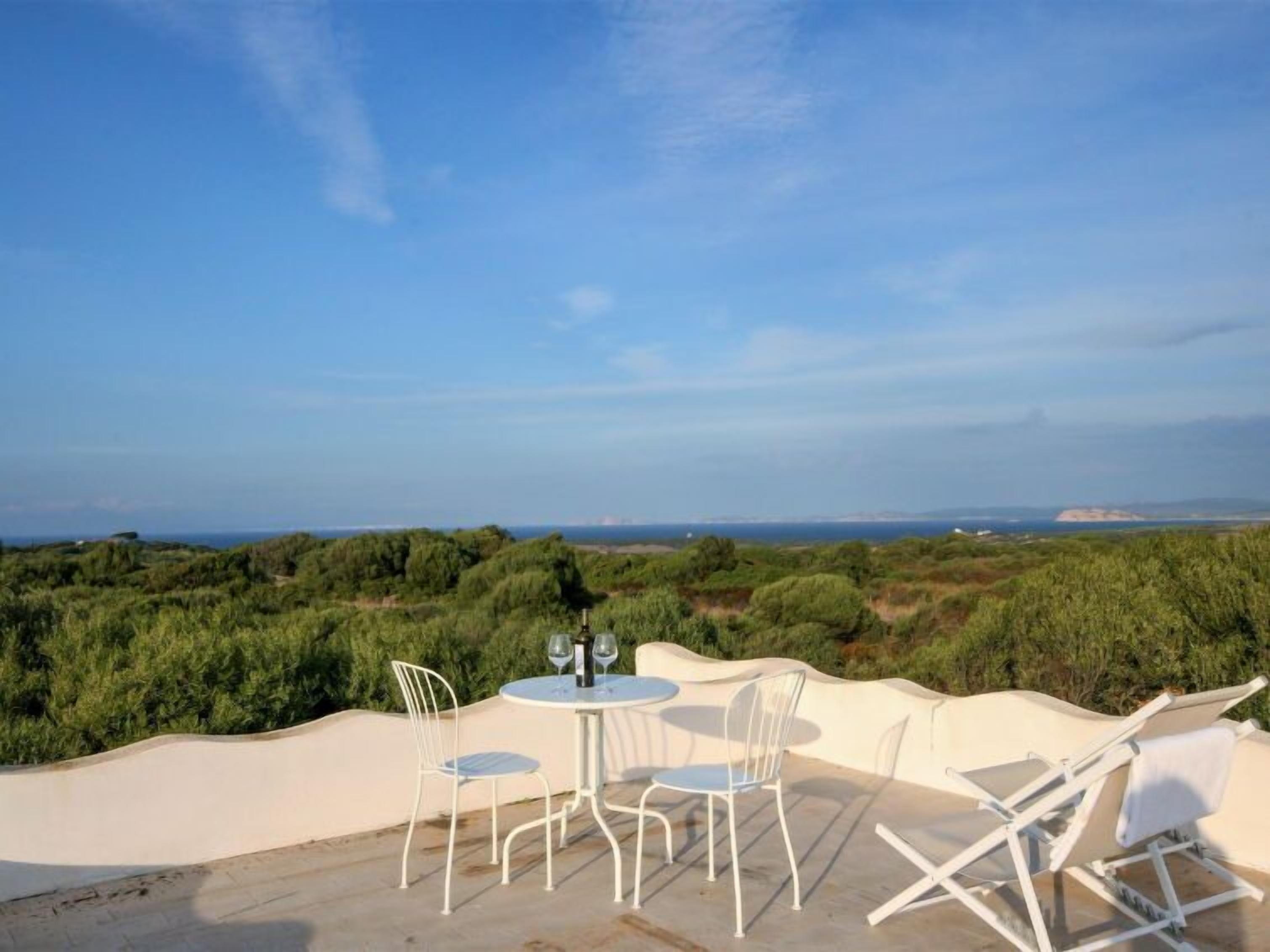 Eine Terrasse mit Tisch und Stühlen mit Blick auf eine Küstenlandschaft.