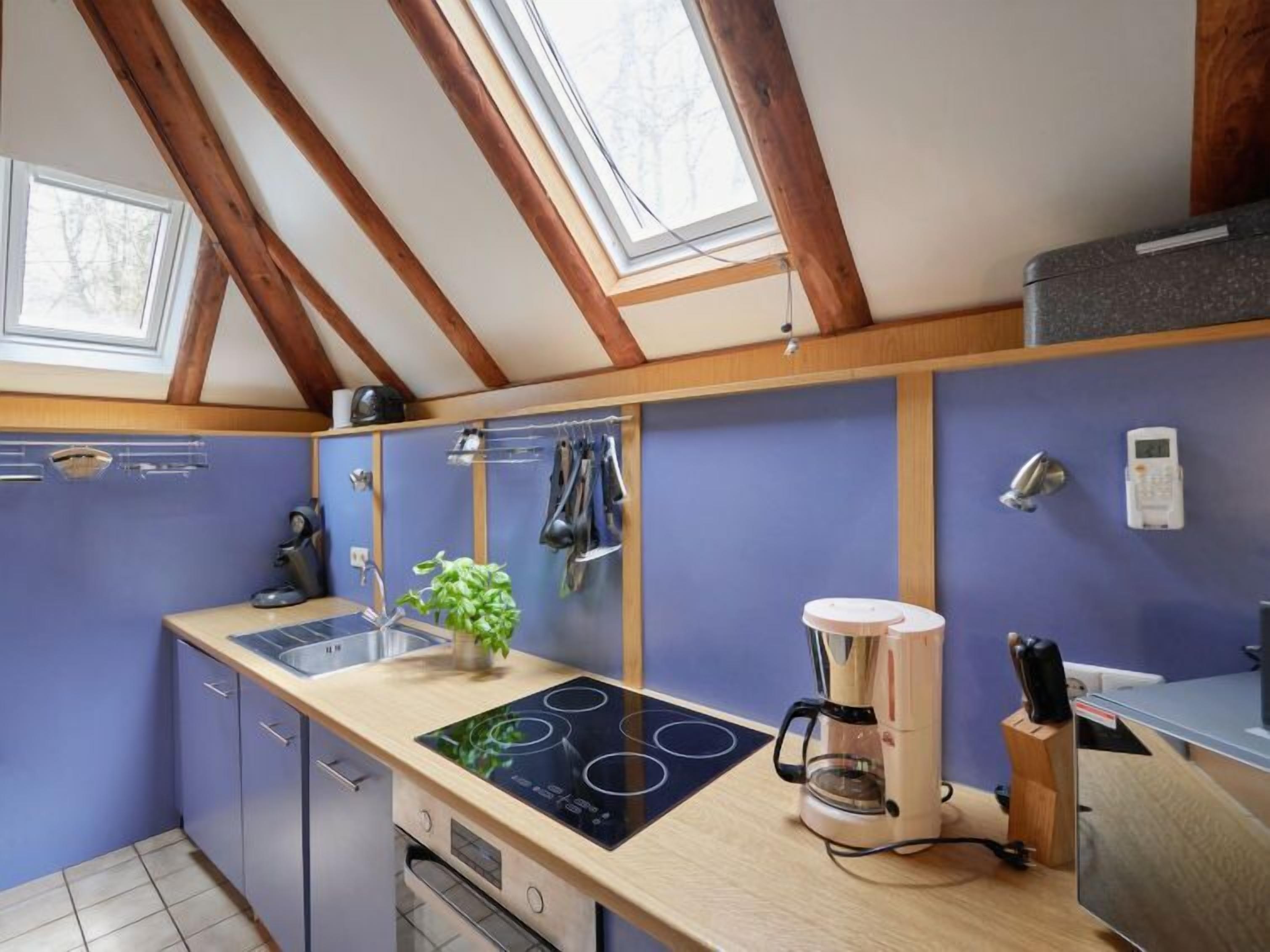 A modern kitchen with a skylight, a built-in stove, and a coffee maker.