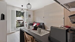 Cozinha moderna com ilha central, área de jantar com sofá e vista para um jardim através de uma porta de correr.