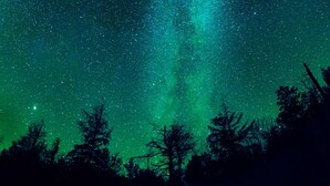 Cielo nocturno con estrellas y aurora verde.