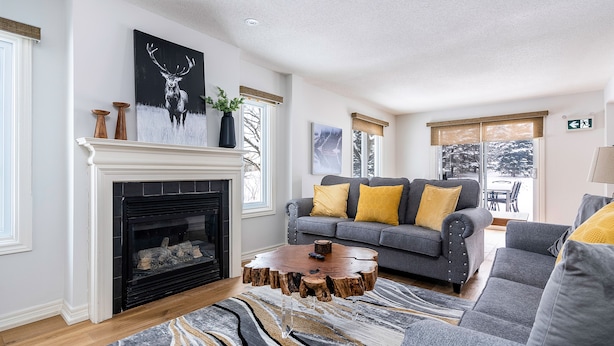 A living room with a fireplace, grey sofa, yellow cushions, and a unique wooden coffee table. - Blue Mountain (The Blue Mountains)