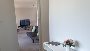 A room with a white desk, a small table, and a sofa in the background. - Kiwiana Gem to enjoy in Reefton (Reefton)