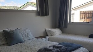 A hotel room with two beds, a nightstand, a window with curtains, and a view of the outside. - Kiwiana Gem to enjoy in Reefton (Reefton)