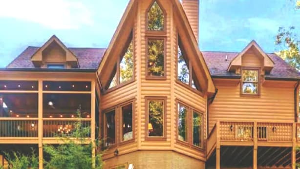 A wooden cabin with a triangular roof, large windows, and a balcony.