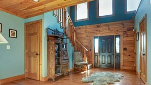 A spacious room with wooden floors, a staircase, and a large window.