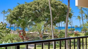 A balcony with a view of a tropical garden and the ocean. - Kaanapali Alii 225 - Expansive 2BR Interior Corner Remodel w/ Partial Ocean Views! (Lahaina)