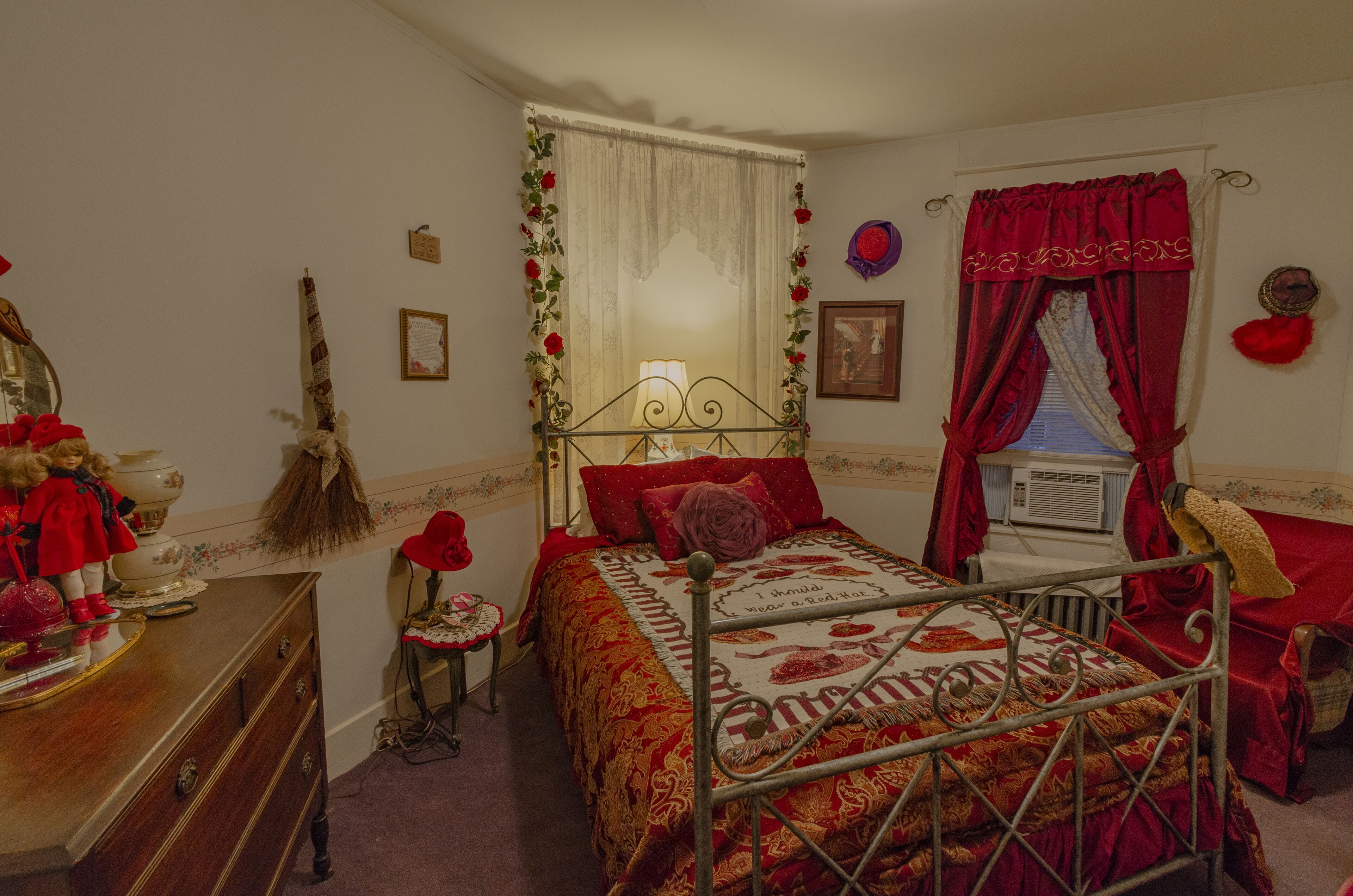 A bedroom with a metal bed frame, a wooden dresser, and a vanity with a mirror.