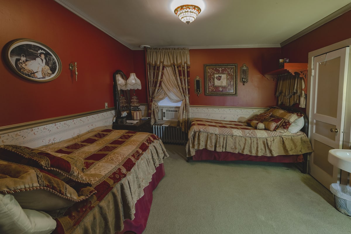 A room with two single beds, a radiator, a mirror, and a framed picture on the wall.