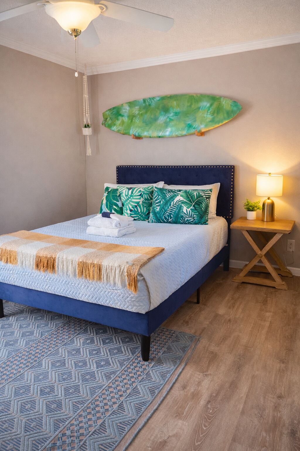 Un dormitorio con cama, mesita de noche, planta en la pared y ventilador de techo.