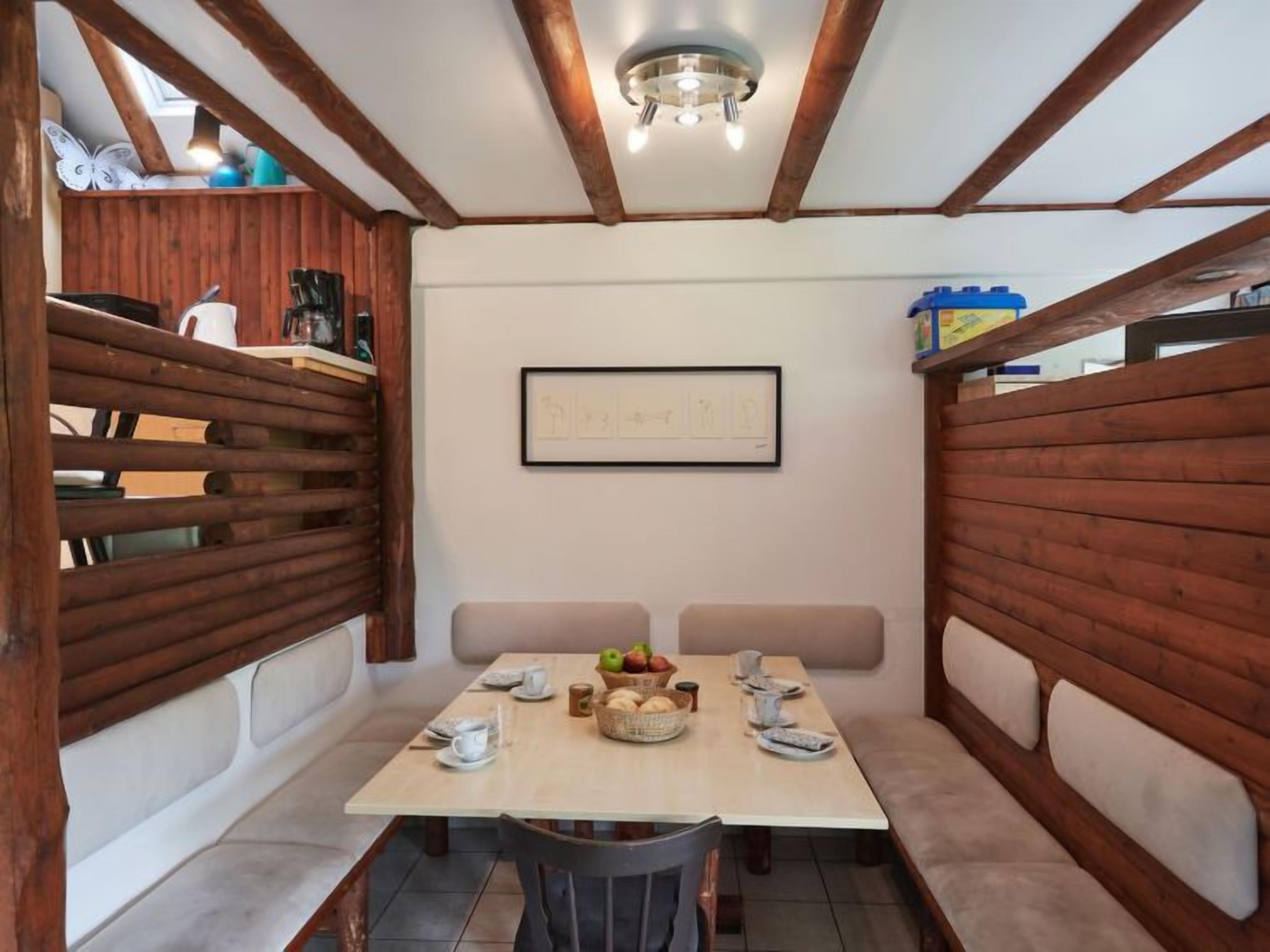 Un espace repas avec une table en bois, des bancs rembourrés et une œuvre d’art encadrée au mur.