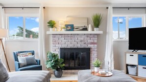 A living room with a brick fireplace, a television, and two armchairs. - Backyard Playset Family Getaway Home STR25-000025 (Marina)
