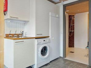 A compact laundry area with a washing machine, a sink, and a shower. - Pulkka 3 by Interhome (Salla)