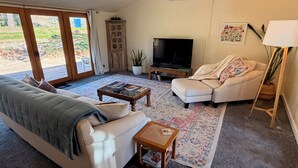 A living room with a sofa, a coffee table, a television, and a potted plant. - Red rock views ♦ Private access to the forestry ♦ The perfect romantic escape (Sedona)