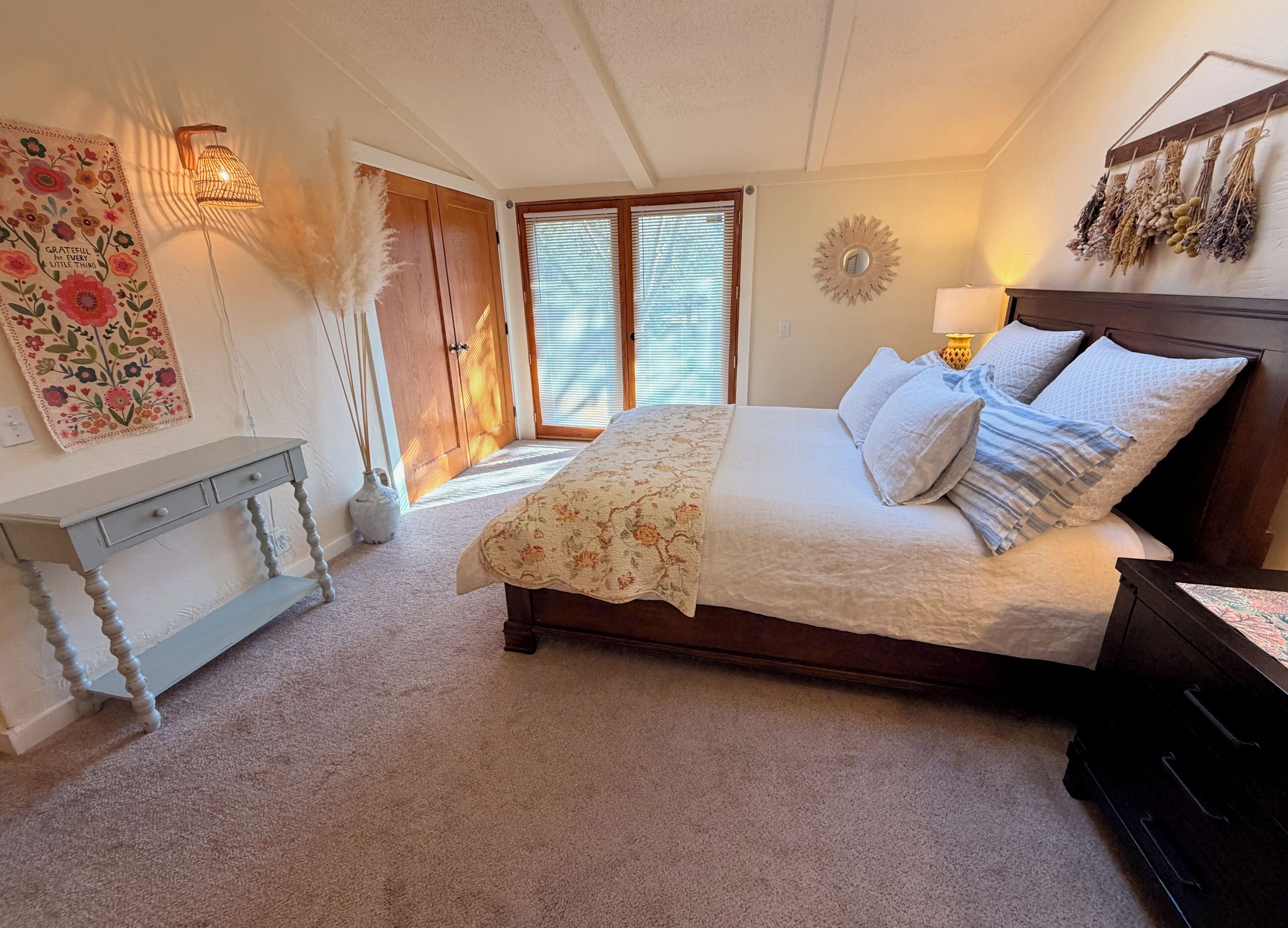 Une chambre à coucher comprenant un lit, une table de chevet, une commode et un miroir fixé au mur.