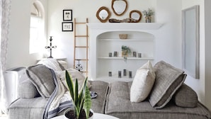 A living room with a grey sofa, a white fireplace mantel, and a ladder leaning against the wall. - Dog-Friendly Cottage w/ Creek, Barn, Game Room, Fire Pit, Hot Tub, Sleeps 10 (Hillsville)