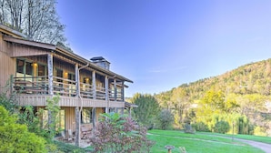A two-story wooden building with a balcony, surrounded by lush greenery and a hillside. - River Access, Mtn Views! All-Season Cullowhee Base (Cullowhee)