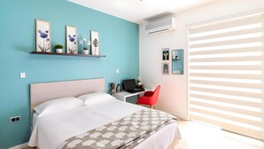 A bedroom with a bed, a desk with a computer, a red chair, and artwork on the walls. - Bright & Relaxing Full Apartment (Cancun)