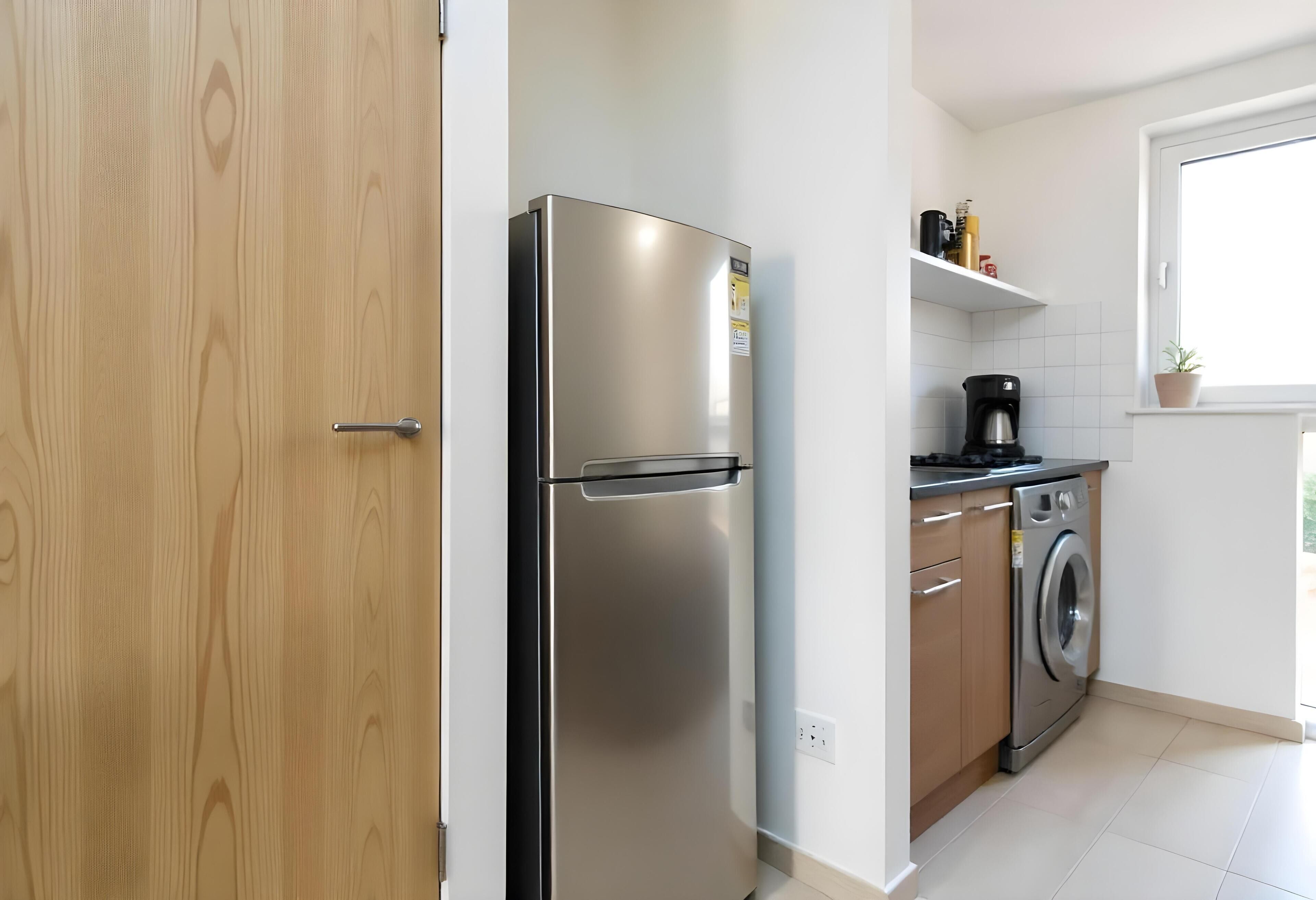 Una cocina moderna con un refrigerador de acero inoxidable, una lavadora y una cafetera.