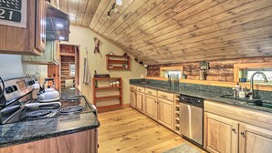 Una cocina con armarios de madera, encimeras de granito, electrodomésticos de acero inoxidable y techo de madera.