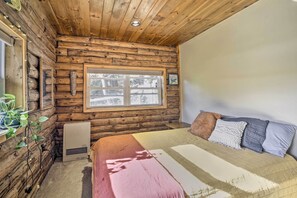 Een houten slaapkamer met een bed, een raam en een radiator.