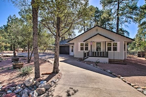 Stroll up to the entrance of this charming single-story home, flanked by two windows, and surrounded by lush trees and a beautifully manicured landscape.
