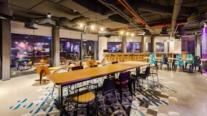 A modern indoor space with a long wooden table, multiple chairs, and a patterned floor. - Tru by Hilton Bac Giang City Centre (Bac Giang)