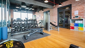 A gym with weightlifting equipment, mirrors, and a brick wall. - Tru by Hilton Bac Giang City Centre (Bac Giang)