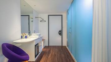 A modern bathroom with a white sink, mirror, and purple chair.