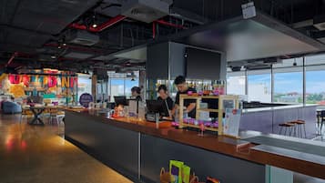 A modern bar area with a counter, seating, and a view of the city.