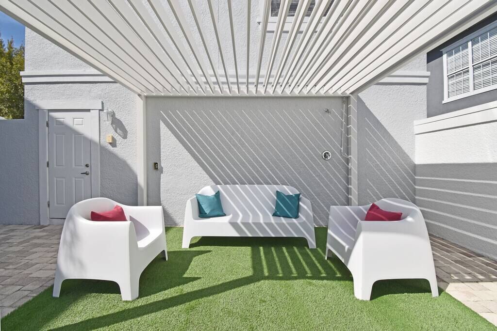 Eine Terrasse mit weißen Gartenmöbeln und Kunstgrasanlage.