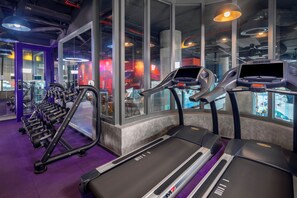 Un gimnasio con cintas de correr, mancuernas y equipo de ejercicio.