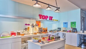 Zona de desayuno buffet con diferentes estaciones de comida, incluyendo yogur, cereales y una estación de café.