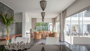 Una sala de estar moderna con un sofá, una mesa de centro y un comedor con una mesa de vidrio.