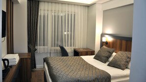 A hotel room with a bed, a desk, a chair, a nightstand, and a TV. - Saka Life Hotel (Erzurum)
