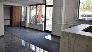 A modern hotel lobby with a reception desk, large windows, and a tiled floor. - Saka Life Hotel (Erzurum)